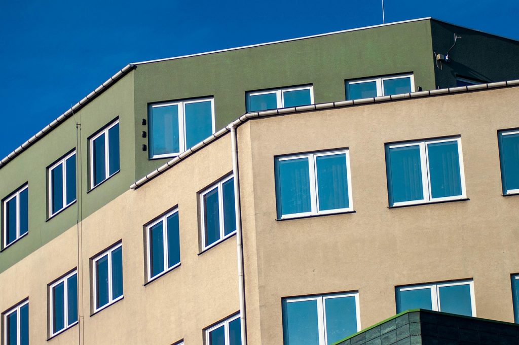 La imagen muestra una moderna fachada de un edificio alto. El diseño se enfoca en líneas limpias y geométricas.