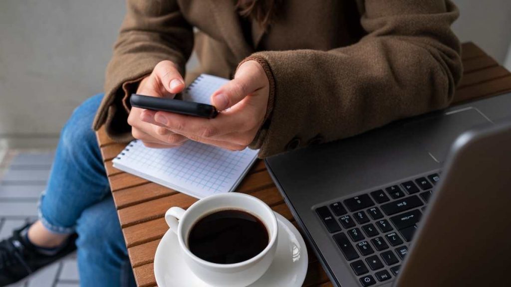 Mujer joven revisando su celular con fondo pastel azul y gráficos de conectividad, representando el crecimiento de los planes pospago en México.